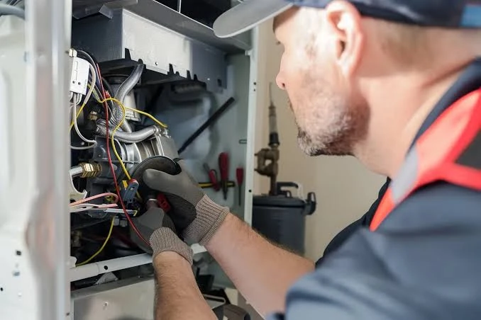 Technician examining wiring and components inside a furnace