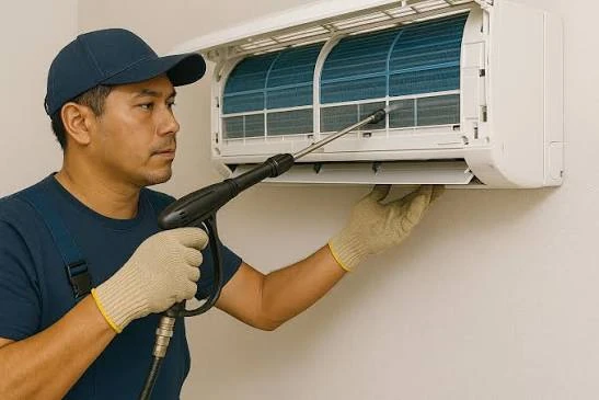 Technician cleaning a wall-mounted indoor air conditioning unit